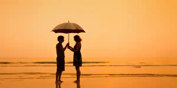 Two people standing together under an umbrella at sunset
